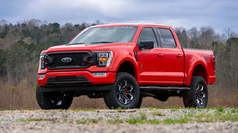 Red Ford F-150 Black Widow lifted truck with black wheels and all-terrain tires
