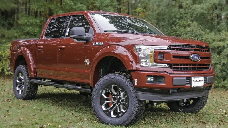Pre-owned red Ford F-150 Black Widow lifted truck on grass